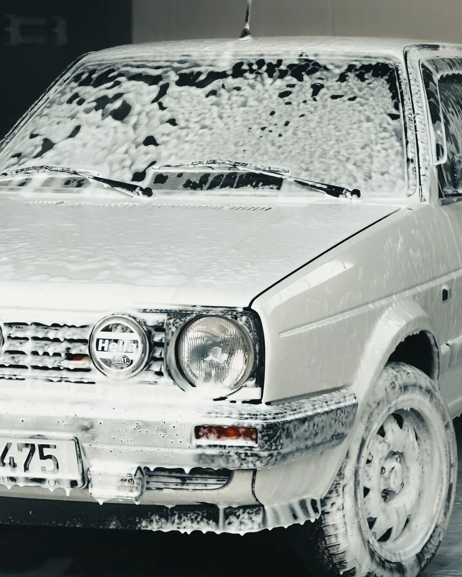 Auto clásico blanco cubierto de espuma de lavado