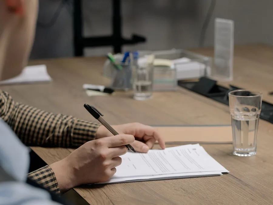 Persona firmando documentos de un trámite vehicular en una mesa